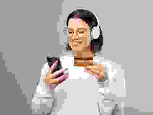 women smiling at her phone with her bank card in her hand